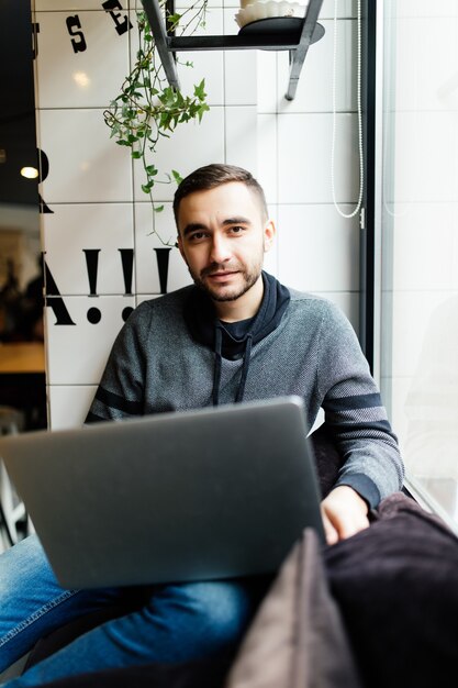 Uomo bello con il computer portatile in un caffè