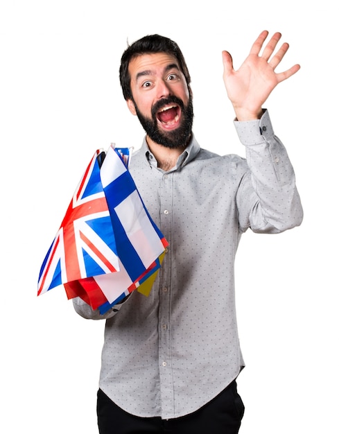 Uomo bello con la barba tenendo molte bandiere e salutando