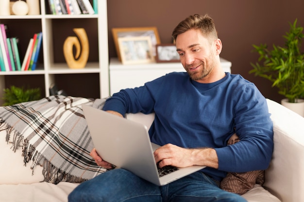 Uomo bello con laptop contemporaneo a casa