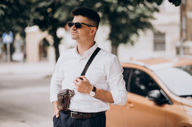 Uomo bello di affari che fa una pausa la sua automobile durante un viaggio d'affari