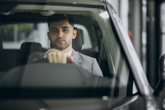 Uomo bello di affari che guida in automobile