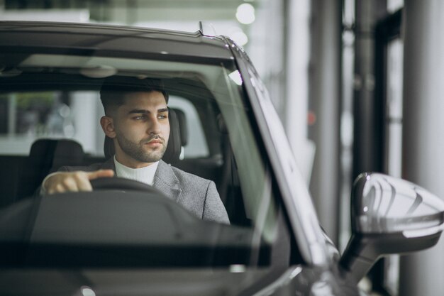 Uomo bello di affari che guida in automobile