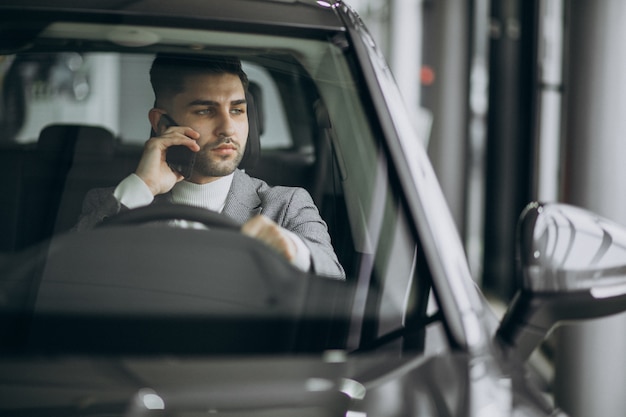 Uomo bello di affari che guida in automobile