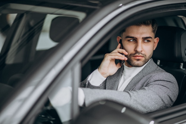 Uomo bello di affari che guida in automobile