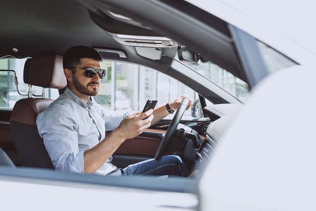 Uomo bello di affari che utilizza telefono nell'automobile