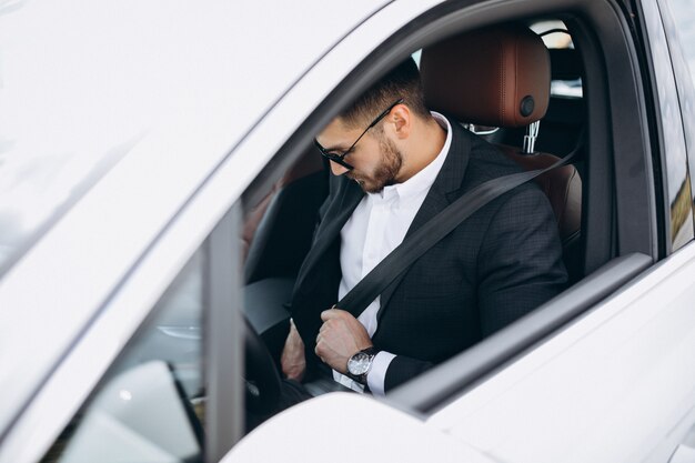 Uomo bello di affari che viaggia in automobile