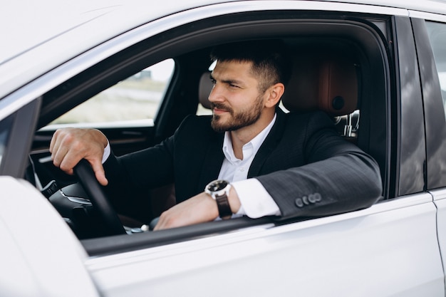 Uomo bello di affari che viaggia in automobile