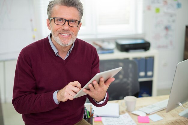 Uomo bello e allegro che lavora sulla tavoletta digitale