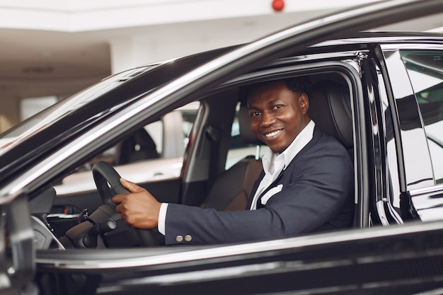 Uomo bello ed elegante in un salone automobilistico