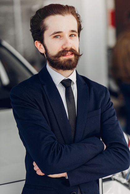 Uomo bello ed elegante in un salone di auto