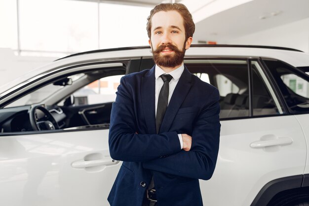 Uomo bello ed elegante in un salone di auto