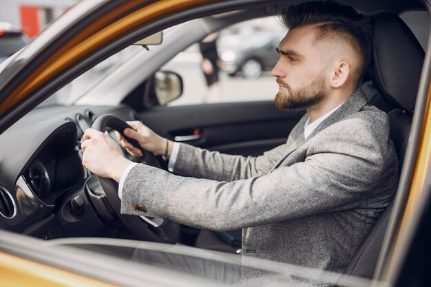 Uomo bello ed elegante in un salone di auto