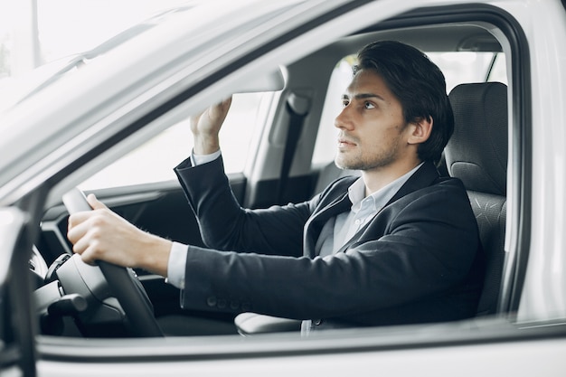 Uomo bello ed elegante in un salone di auto