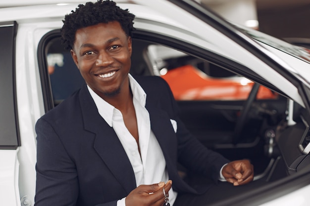 Uomo bello ed elegante in un salone di auto