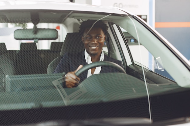 Uomo bello ed elegante in un salone di auto