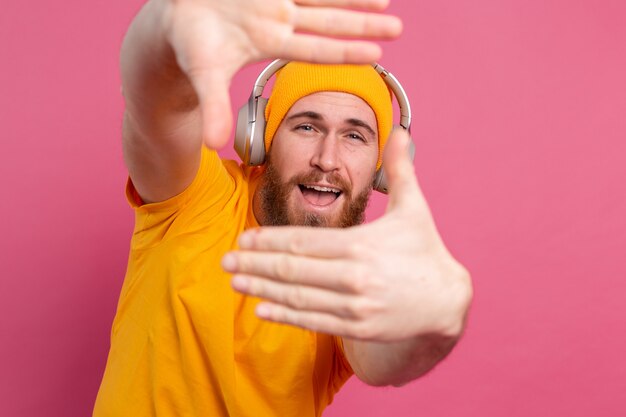 Uomo bello in ascolto casuale di musica con le cuffie isolato su sfondo rosa