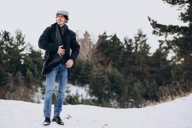 Uomo bello in piedi in un parco invernale