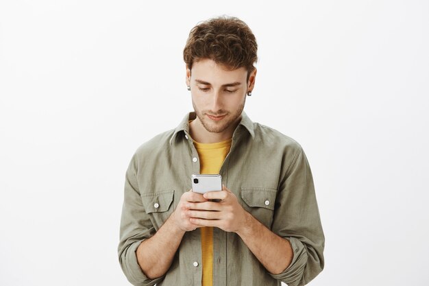 Uomo bello in posa con lo smartphone in studio