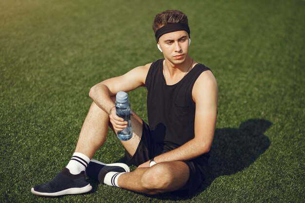 Uomo bello in un'acqua potabile del clother di sport in un parco