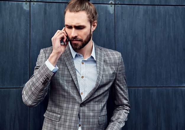 Uomo bello in vestito a quadretti grigio che parla con lo smartphone