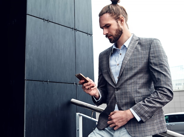 Uomo bello in vestito a quadretti grigio con lo smartphone