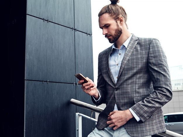 Uomo bello in vestito a quadretti grigio con lo smartphone