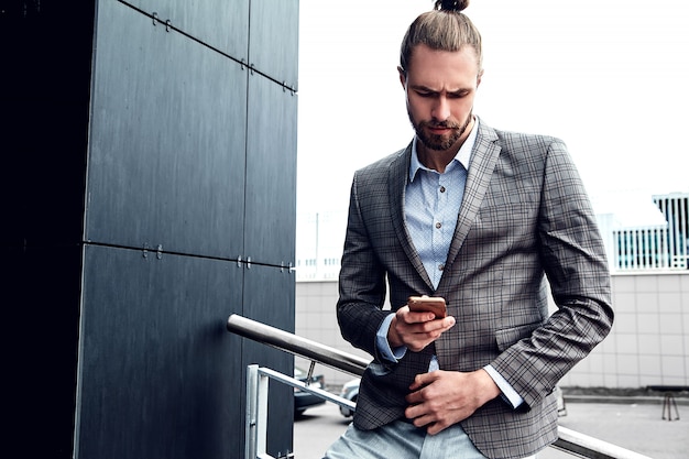 Uomo bello in vestito a quadretti grigio con lo smartphone