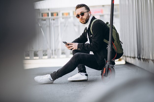 Uomo bello sul motorino che compera online sul telefono