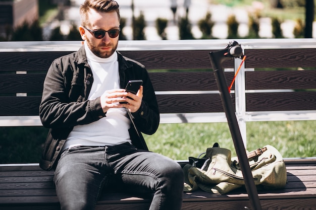 Uomo bello sul motorino che compera online sul telefono