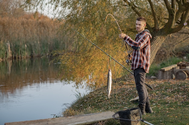 Uomo bello vicino al fiume in una mattina di pesca