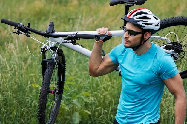 Uomo ben fatto che trasporta la sua bici