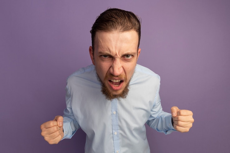 Foto gratuito uomo biondo bello infastidito tiene i pugni e guarda davanti isolato sul muro viola