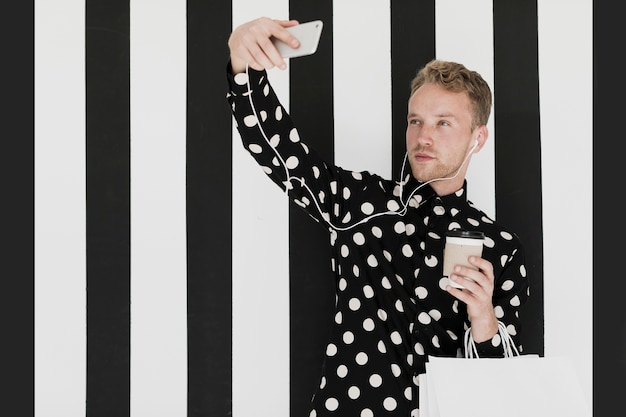 Uomo biondo con la camicia che prende un selfie