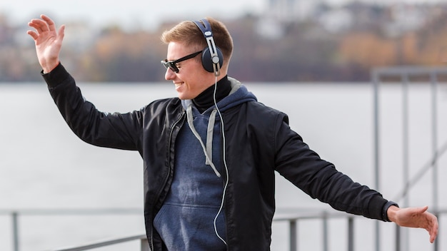 Uomo biondo di smiley di vista laterale che ascolta la musica e ballare