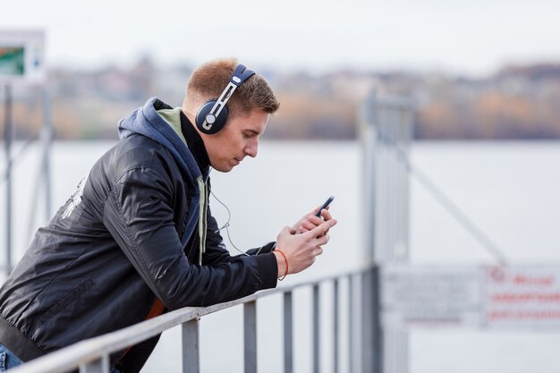 Uomo biondo di vista laterale che ascolta la musica fuori