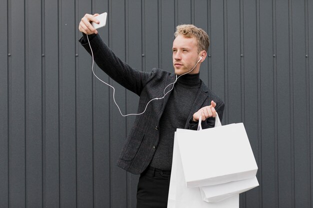 Uomo biondo nel nero che prende un selfie con lo smartphone