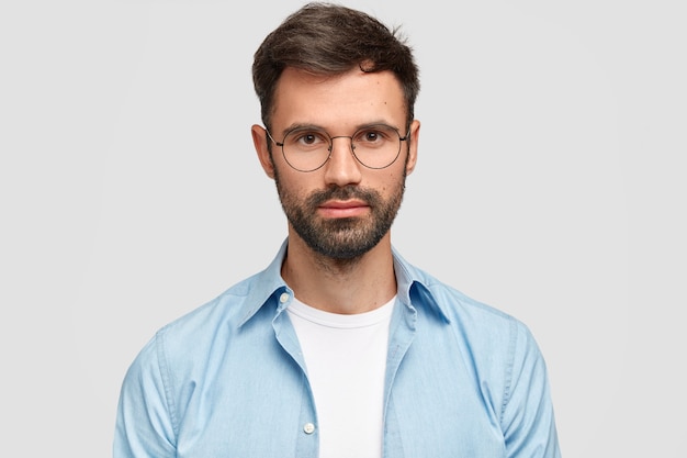 Uomo Brunet che indossa occhiali rotondi e camicia blu