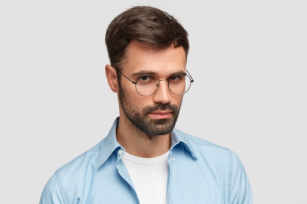 Uomo Brunet che indossa occhiali rotondi e camicia blu
