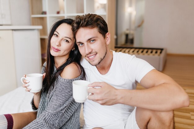 Uomo caucasico ispirato che beve caffè con la fidanzata domenica mattina