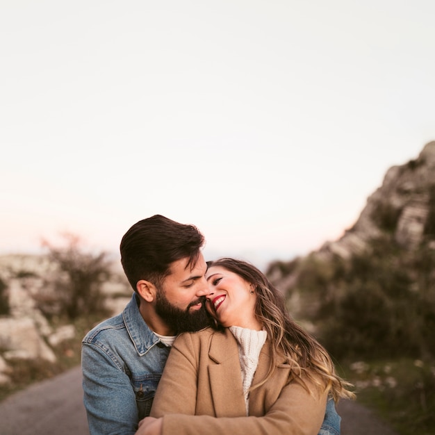 Uomo che abbraccia bella donna sulla strada di montagna