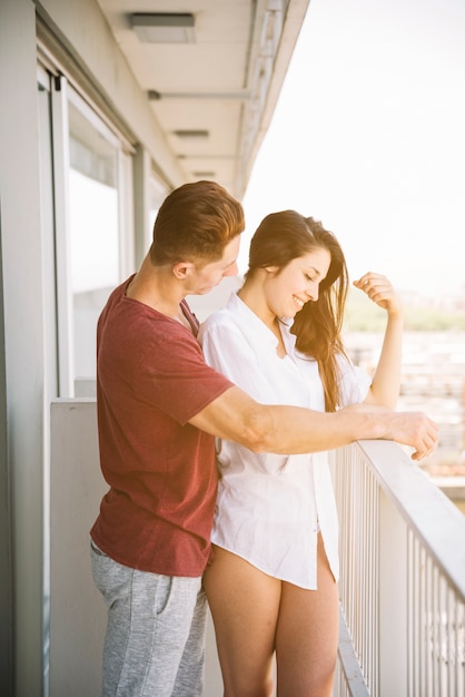 Uomo che abbraccia la donna da dietro sul balcone