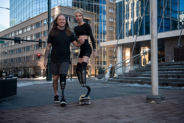 Uomo che aiuta la donna con disabilità alle gambe a fare skateboard in città