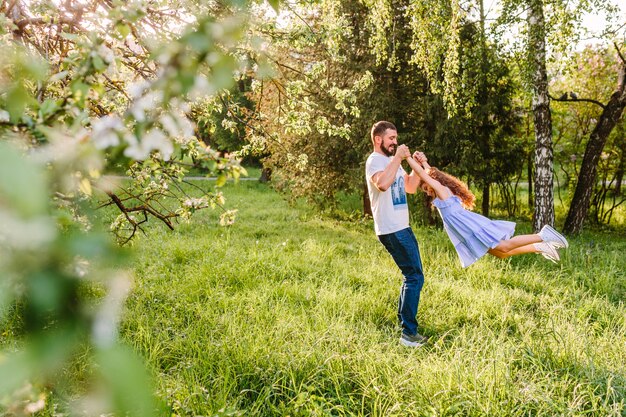 Uomo che alza la figlia nel parco