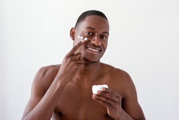 Uomo che applica la crema per il viso colpo medio