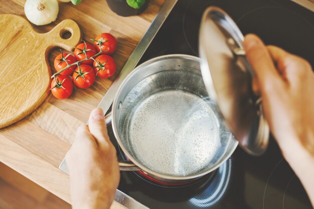 Uomo che apre il coperchio del piatto iniziando a cucinare