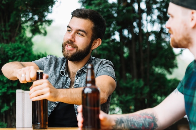 Uomo che apre la bottiglia di alcol con il suo amico