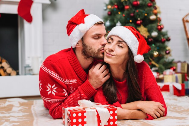 Uomo che bacia donna vicino all&#39;albero di Natale