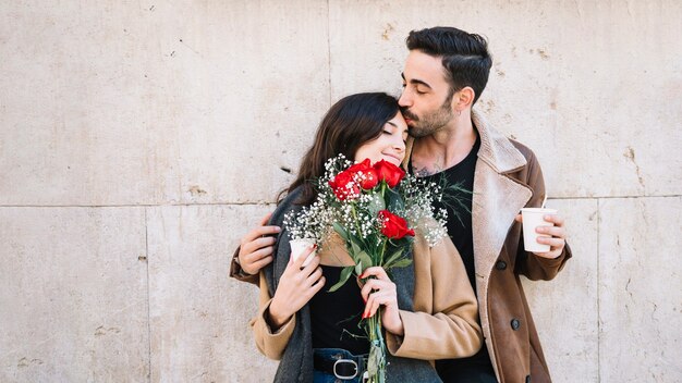 Uomo che bacia la donna con bouquet