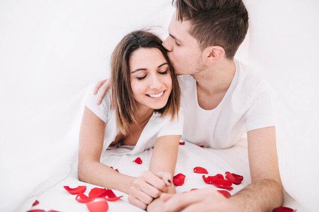 Uomo che bacia la donna sui petali di rosa