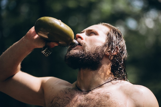 Uomo che beve acqua nella foresta